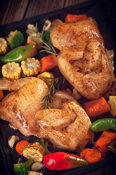 Roasted chicken with vegetables on baking plate 