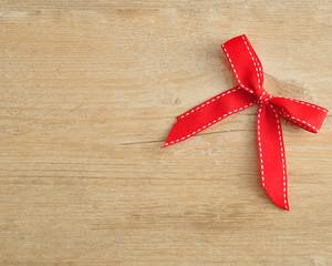 A red bow made out of ribbon on a wooden background