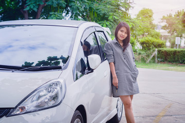 Portrait happy smiling young attractive woman standing next to new white car