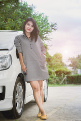 Portrait happy smiling young attractive woman standing next to new white car
