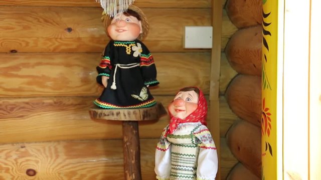 Wooden wall and window decorated in Russian style. Dolls, toys, shawls, wooden products.