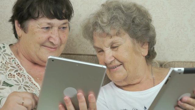 Old women holding the silver digital tablets