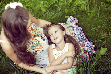 Mother and daughter in a beautiful floral sundresses in the summ