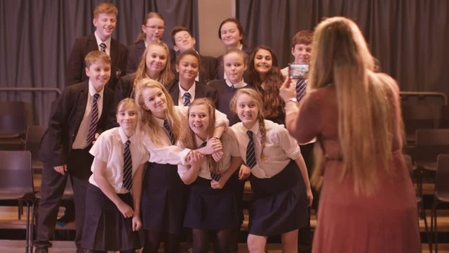  Teacher takes a photo of her students in school theatre