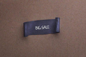 paper sheet with BIG SALE text on wooden background.