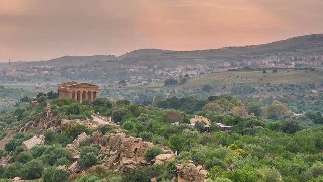 Sunset timelapse of Valley of temples in Agrigento in Sicily with flying clouds and night illumination.
