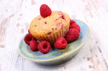 Fresh baked cupcake with raspberries and fruits on old wooden background, delicious dessert