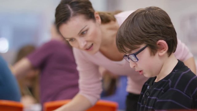  Teacher working with little boy in school lesson