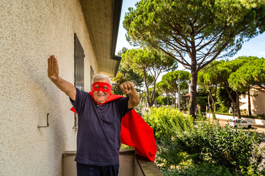 senior posing as superhero with red cloack and mask