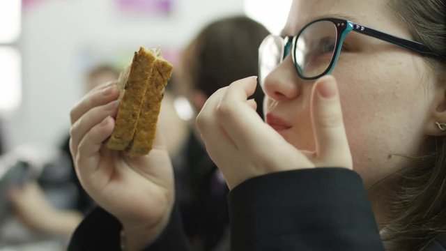 Close up portrait of girl eating a sandwich in school cafeteria
