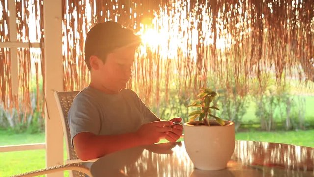 Little boy gaming on mobil phone at the cafe. Smartphone addiction