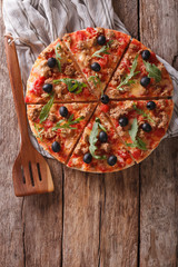 Sliced pizza with tuna, olives and arugula close-up. Vertical top view
