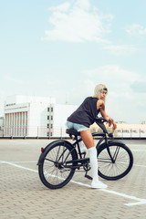 Pretty blonde woman with bike in city