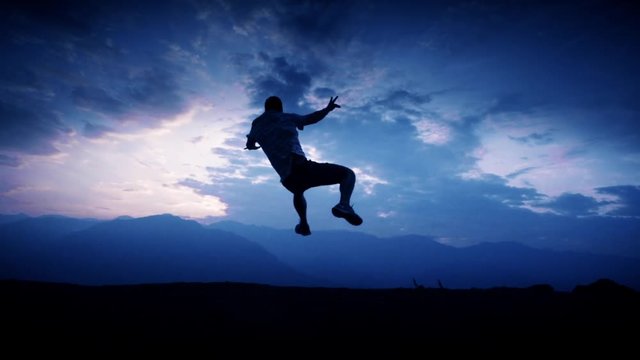 Silhouette of male practicing martial arts on the top of a mountain. Slow motion