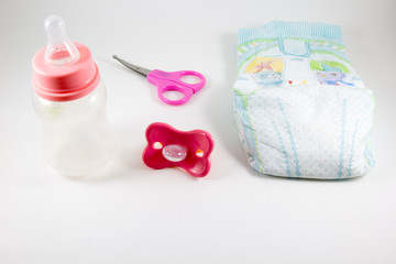 Baby bottle, nipple and scissors on a white background