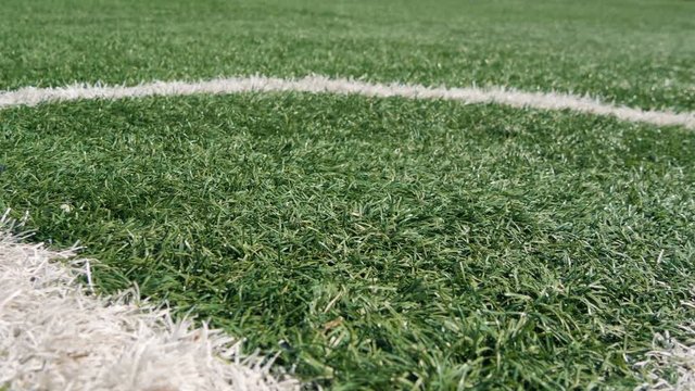 Close up of the out of bounds line on a turf football field. Green grass