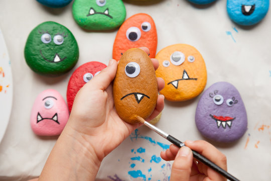 Child painting a stone for making a monster craft