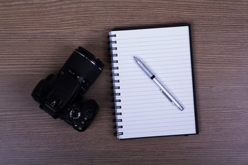 Notebook and camera on a wooden surface