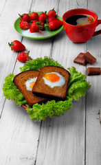 Fototapeta na wymiar two fried eggs in toast on the salad, cup of coffe stars to