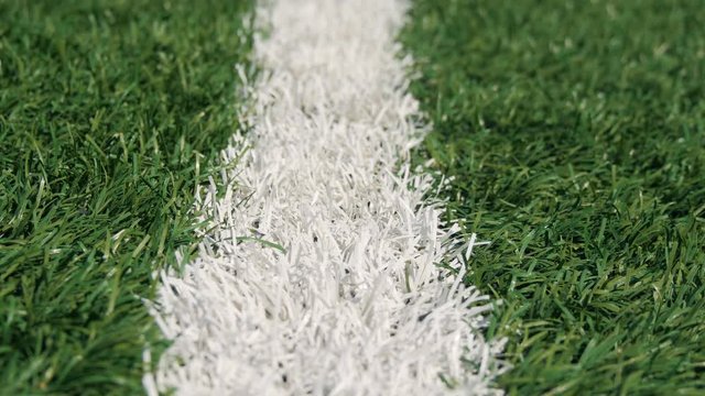 Close up of the out of bounds line on a turf football field. Green grass