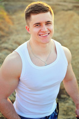 Portrait of a young attractive man laying down on white sand while on vacations on the beach.