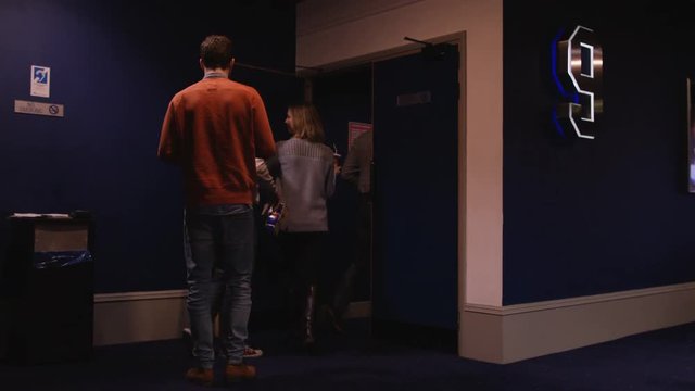  Cinema worker taking tickets from customers before they go into movie theatre