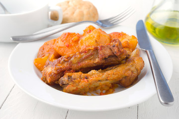 serving of pork stew in white dish on wooden board