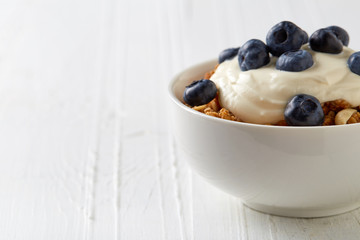 Bowl of whole grain muesli with blueberries and yogurt on white
