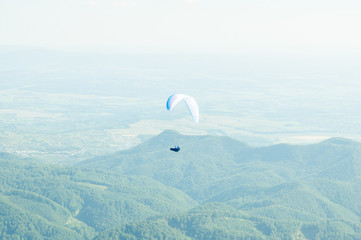 Fototapeta na wymiar Paraglider flying over the green hills