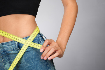 Athletic slim woman measuring her waist by measure tape