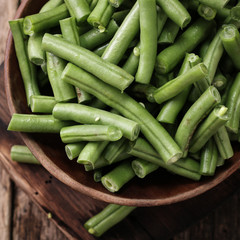 Bunch of freshly picked green beans on a wooden surface.