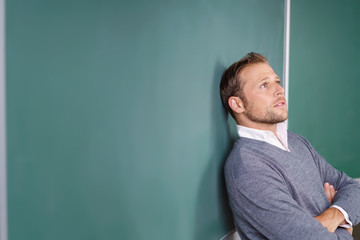 lehrer lehnt an der tafel und schaut nachdenklich nach oben