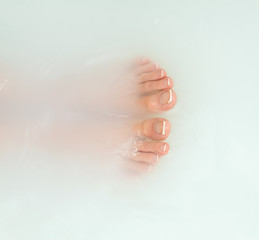 Woman legs in bath with milk. SPA treatments for skin care.