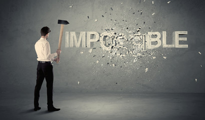 Business man hitting impossible sign with hammer