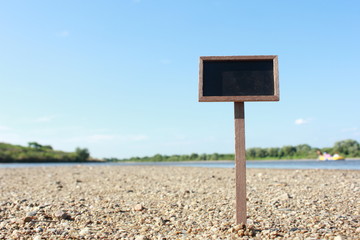 Blank blackboard with sand and blue sky background
