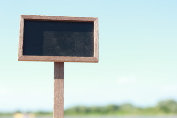 Blank blackboard with sand and blue sky background
