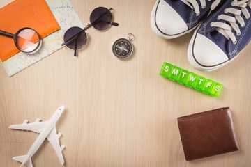 Flat lay of travel planning and equipment necessary on wooden floor background - Holiday travel concept.