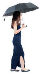 young woman in dress walking under an umbrella. Rear view people collection.  backside view of person.  Isolated over white background. The dark curly girl in a blue evening dress is in the side under