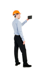 Backview of business man in construction helmet stands and enjoys tablet or using a mobile phone. Standing young guy. Rear view people collection.  backside view of person.  Isolated over white