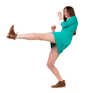 skinny woman funny fights waving his arms and legs. Isolated over white background. Long-haired brunette in a green dress fights feet.