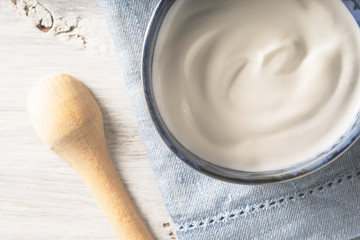 Sour cream on the ceramic dish on the white wooden table top view