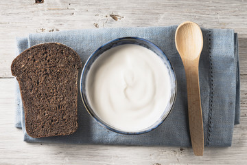 Sour cream on the ceramic dish with bread on the white wooden table horizontal