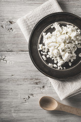 Fresh cottage cheese on the  metal plate on the white wooden table vertical