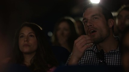  Man laughing loudly in cinema audience making his girlfriend embarrassed