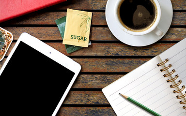 workspace with coffee cup, tablet pc and note paper on old wooden table, close-up, over light