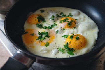  fried eggs seasoned with herbs and pepper in an  metal pan and ready to be served for a delicious breakfast - 118457074