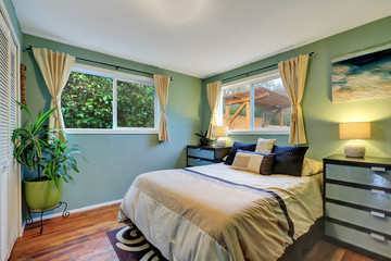Blue bedroom interior with king size bed, hardwood flooe and beige curtains