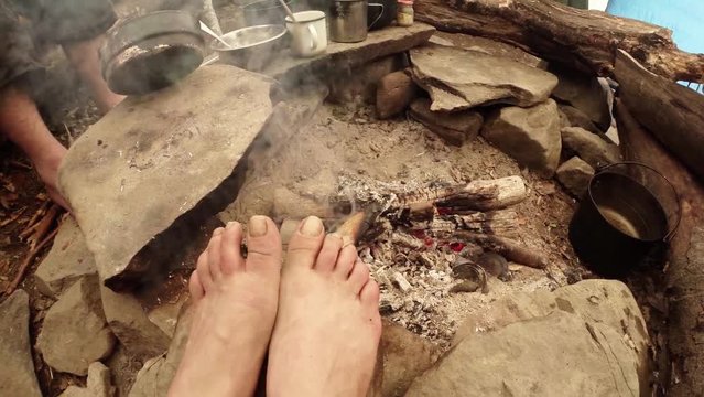 Human Feet Are Heated by Smoldering Bonfire Staying on the Stone