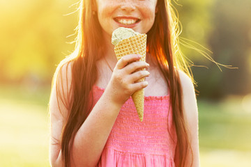 redhead girl with freckles eating ice cream in sunset light