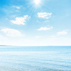 Fototapeta na wymiar blue seascape with sun over clouds